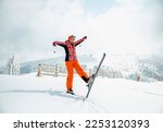 Woman skier with ski equipment on snow at mountain. Adult female in an orange color ski suit  skiing on a snowy day. Smiling active woman on a winter Holiday vacation. Copy space