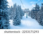 Skiing and snowboarding ski resort background. Ski chairlift and winter panorama at ski resort. View on the ski lift and beautiful snowy mountain with pine trees. Copy space