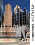 Small photo of Pittsburgh, PA, USA May 6, 2014 Two workers walk around the fountains and obelisk of the PPG Plaza at lunchtime in Pittsburgh Pennsylvania