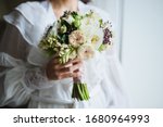 Beautiful wedding bouquet in bride's hands, wedding underwear, details. The girl in a white dress holding a bouquet of white, pink flowers and greenery, decorated with silk ribbon