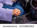 Small photo of Close up Young woman hand on manual gear shift, shifting gearbox in car.Driver woman hand holding manual transmission or variable speed drive in car, shifting gear stick before driving car.