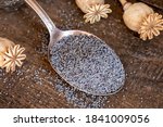 Poppy seeds on a metal spoon on a table