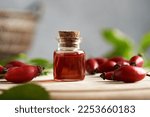 A glass bottle of rose hip seed oil with fresh berries on a table