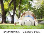 Woman reading book in grass under tree with cup of coffee. Relax in summer time holiday laying on the grass field comfortable feeling.