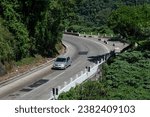 Small photo of PETROPOLIS, RIO DE JANEIRO - BRAZIL - DEC 18, 2018: View of Washington Luiz highway (BR-040) nearby Mirante do Cristo observation deck while a Renault Logan pass by in a summer afternoon sunny day.