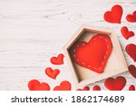 Top view of red heart in a house decorated with small hearts on wooden background. Valentine's day. Home sweet home concept.