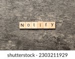 Small photo of NOTIFY word written on wood block. NOTIFY text on cement table for your desing, concept.