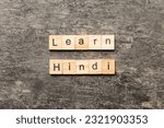 Small photo of Learn Hindi word written on wood block. Learn Hindi text on table, concept.