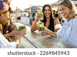 Small photo of Young women celebrating at beach chiringuito, focus on brunette woman with toothy smile