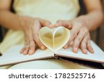 hands make a book paper shape heart. Love concept.