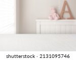 Small photo of Girls bedroom background. Pink, small teddy bear, sitting on top of a white bed frame next to a giant wooden letter A. Place a digital product mockup on the perspective white table.
