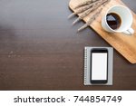 Small photo of Desk table top overhead work space layout right smart phone isolated on notebook and coffee cup white holiday working