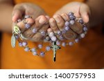 Rosary in hand. Young junior lady holding rosary with open hand. Female hands holding a rosary with Jesus Christ Cross Crucifix. Month of Rosary, Christian Catholic religious symbol of faith concept.