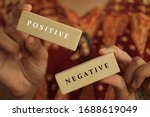 Small photo of Young woman holding antonym word sign of positive and negative. Two wooden blocks in hands closeup with life option concept. Choose positive mind or negative thought.