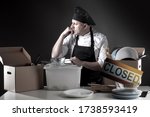 Bankruptcy. Restaurant owner overwhelmed by finance problems. Plate closed symbolizes ruin. Depressed cook closed restaurant. Horeca crisis. Dishes in boxes. Closed restaurants for COVID-19 pandemic