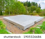 Concrete foundation next to trees. Construction near forest. Construction site with foundation. Foundation as a symbol of construction of a cottage. Building of a country cottage.