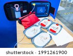 Automatic external defibrillator. Portable defibrillator on a wooden table. Defibrillator for medical care. Device for provision of emergency medical care. Automatic cardioverter with nursing manual