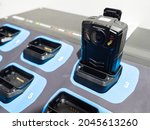 Small photo of Chest video recorder. Body-worn video recorder at charging station. Device for recording employee movements. Concept - sale of portable video recorders. Close-up DVR equipment. Garment DVR