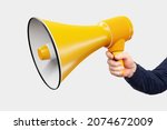Small photo of Loudspeaker in hand on white background. Loudspeaker as symbol of agitation and propaganda. Large yellow loudspeaker. Man with megaphone. Concept sale sound equipment. Isolated hand with gramophone