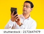 Small photo of Surprised man with calculator. Human is stunned by large taxes. Dazed man holding calculator. Concept of big bills for payment. Guy with calculator on yellow. Businessman surprised by expenses