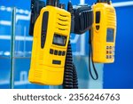 Small photo of Electronic walkie talkies. Two walkie-talkies weigh on glass. Portable walkie talkies. Radios with electronic screens. Walkie talkie for wireless communication. Handheld transceivers in yellow case