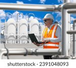 Small photo of Man works at chemical plant. Factory engineer with laptop. Chemical industry. Man plant technologist. Industrialist stands on territory of plant. Pipes and storage tanks near engineer