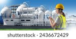 Small photo of Woman works at chemical factory. Petrochemical production plant. Girl engineer with tablet computer. Exterior of chemical factory behind woman. Industrialist in yellow vest and helmet