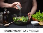 Woman chef in the kitchen preparing vegetable salad. Healthy Eating. Diet Concept. A Healthy Way Of Life. To Cook At Home. For Cooking. The girl sprinkles salt in a salad on a dark background