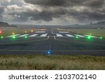 Small illuminated runway of a country airport. Dark dramatic cloudy sky. Aviation industry. Nobody. Selective focus. Dangerous flying conditions