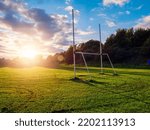 Small photo of Small tall goal post on training field for rugby and Irish national games hurling, camogie, Gaelic football and soccer at sunset. Rich green and blue colors. Sun flare and blue sky. Sport area