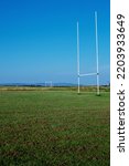 Small photo of Field with tall goal posts for Irish National sports on green grass against clear blue sky. Rugby, hurling, camogie and Gaelic football training ground. Nobody. Popular sport in Ireland.