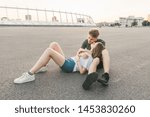 Small photo of Portrait portrait of a beautiful lovers couple hugging in the street in a deserted place against the backdrop of urban landscape. Street portrait of a young couple kissing on a summer evening.