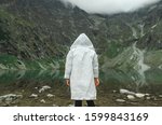 Portrait from back of person in white raincoat on background of beautiful lake on top of mountain. Background. Man hiking in the mountains. Man and untouched nature concept.