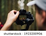 Small photo of Close photo, the camera on the stabilizer in the hands of a man takes a beautiful young couple. Shooting in nature in the worst untouched forest, the cameraman uses a gimbal.