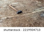 Small photo of The handyman has left his sledge hammer on the dry parched ground. The tool is designed to deliver blunt force to an area or object.