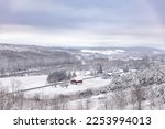 Peaceful winter scene with a red barn in the middle of a snowy hilly field. Upstate New York