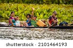 Small photo of Orinoco, Venezuela - 11-23-2021: Native Orinoco tribe people in traditional boat in Venezuela waving at camera