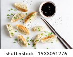 Gyoza, fried asian dumplings served with soy sauce, scallion and sesame seeds on marble background. Top view