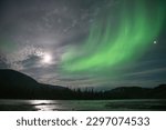 Northern lights and a full moon in the night sky in Northwest Territories on the Nahanni River, Canada. Night photography