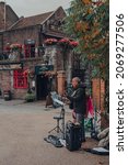 Small photo of London, UK - October 17, 2021: Busker performing in front on the Anchor, a historic pub on the bank of River Thames, on an autumn day.