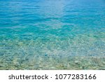 Transparent shallow water with rocky bottom, fading away to deeper area at top.Crystal clear water with transparent surface shine under the bright summer sun. Colorful underwater stones.