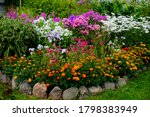Small photo of multicolored flowerbed on a lawn. horizontal shot. selective focus.Perennial garden flower bed in spring at flower show.Colorful flower bed with Gazania and Begonia,phloxes
