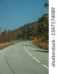 Small photo of Deserted curve road through hilly landscape with dry bushes and green trees, on sunny day near Castelo Branco. Friendly and important city, it was a former bishopric in the central region of Portugal.
