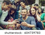 A group of friends on the steps of a house porch, looking at a smart phone selfy on the screen
