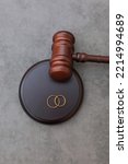 Small photo of Law theme. Judge gavel wedding rings on concrete stone grey background. Divorce proceedings. Mallet of judge deciding on marriage divorce, marital agreement, legalities of divorce