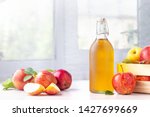 Healthy organic food. Apple cider vinegar in glass bottle and fresh red apples on a light background.