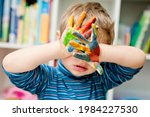 Small photo of little pre-school artist. Boy with painted hands hiding his eyes. Important international symbols: adoption, custody, Children's Right to Protection, care of orphans, parenthood, parentage