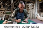 Small photo of Handcrafted leather worker sits farts cowhide with cutter according pattern drawn on leather, according pattern drawn before cutting, so that pattern cut on cowhide comes out beautiful sharp.