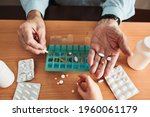 Senior man organizing his medication into pill dispenser. Senior man taking pills from box. Healthcare and old age concept with medicines. Medicaments on table