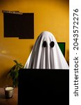 Small photo of Ghost writing an article on laptop n home office with "can't fix stupid" sign on the wall. Ghostwriter in a desk. Person working or studying in halloween. Green screen computer on the back.